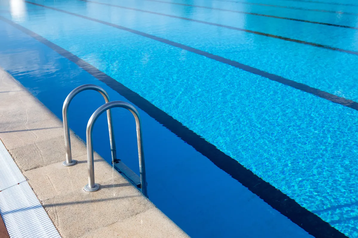 a pool with a ladder in it and a swimming pool in the background