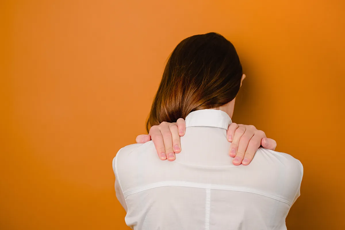a woman with her back to the camera, holding her neck
