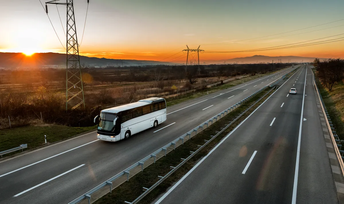 arafed bus on a highway with a sunset in the background