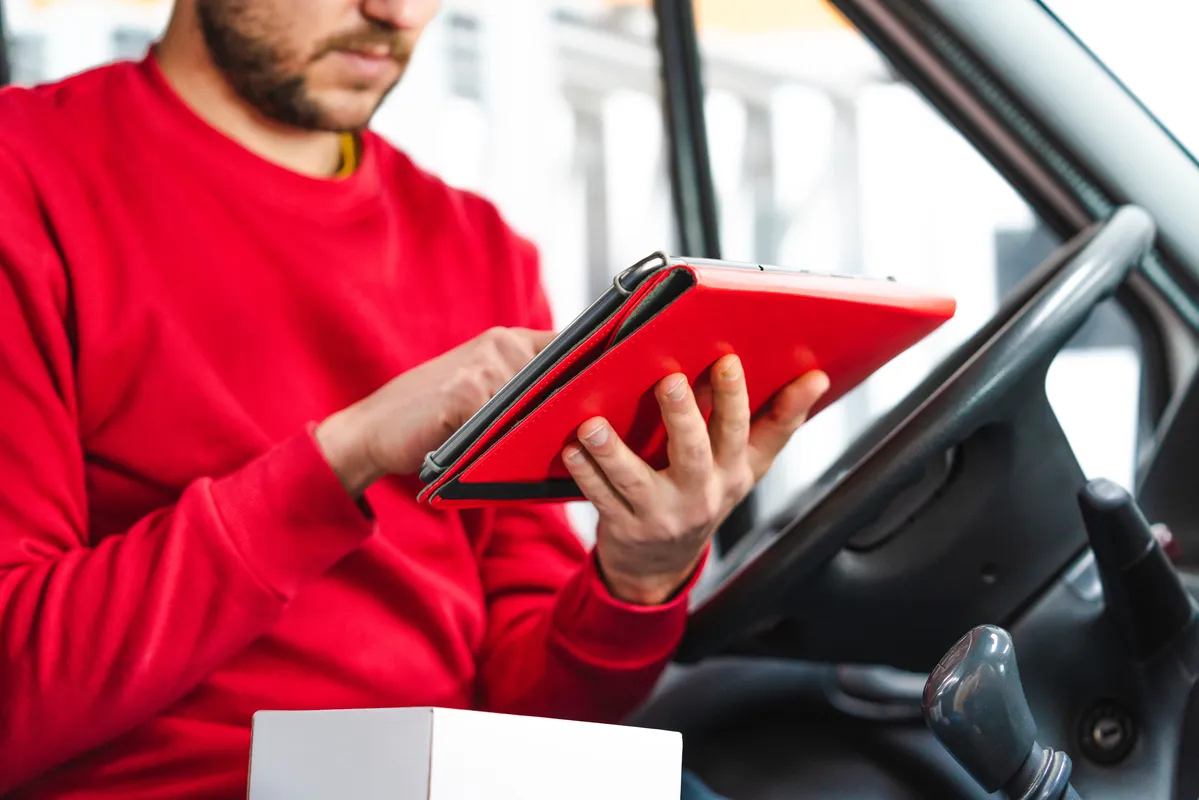 arafed man in a red shirt using a tablet computer in a car