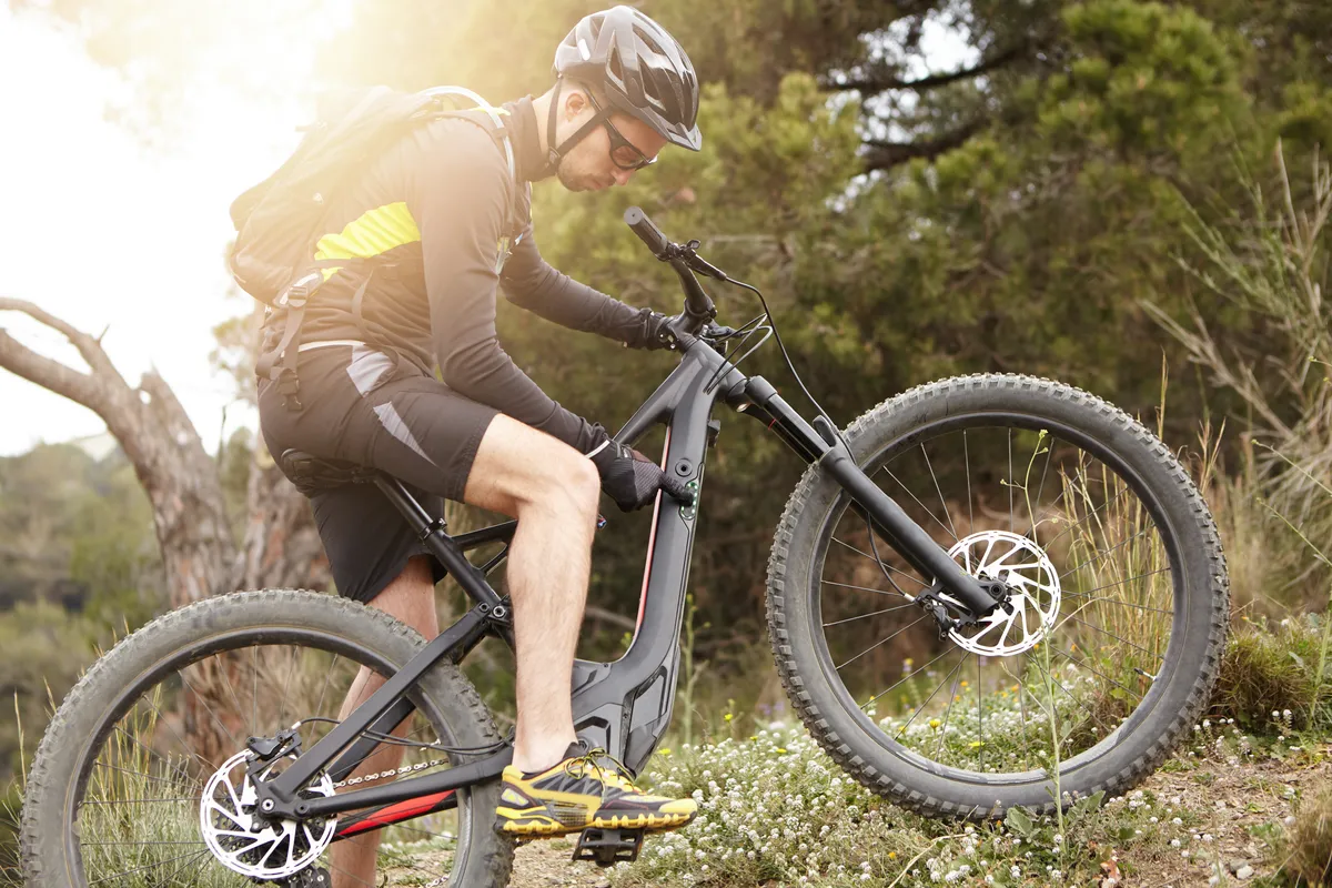 arafed man riding a bike on a trail in the woods