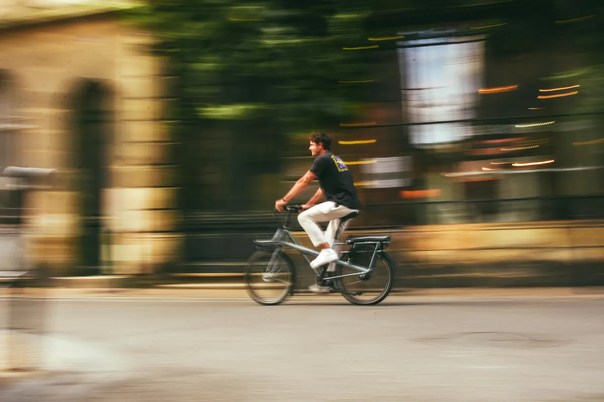 blurred image of a man riding a bike down a street