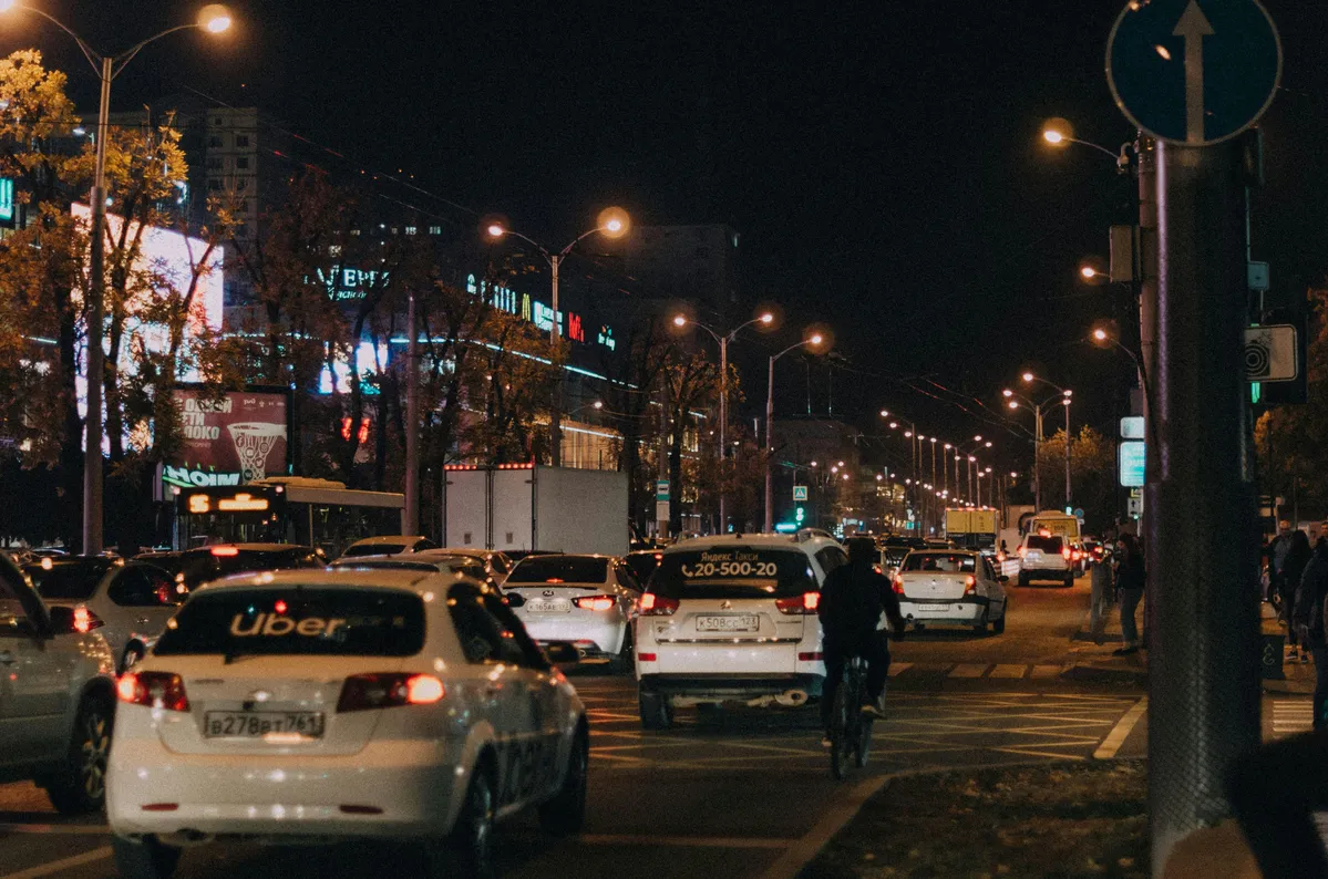 cars and motorcycles are stopped at a busy intersection at night