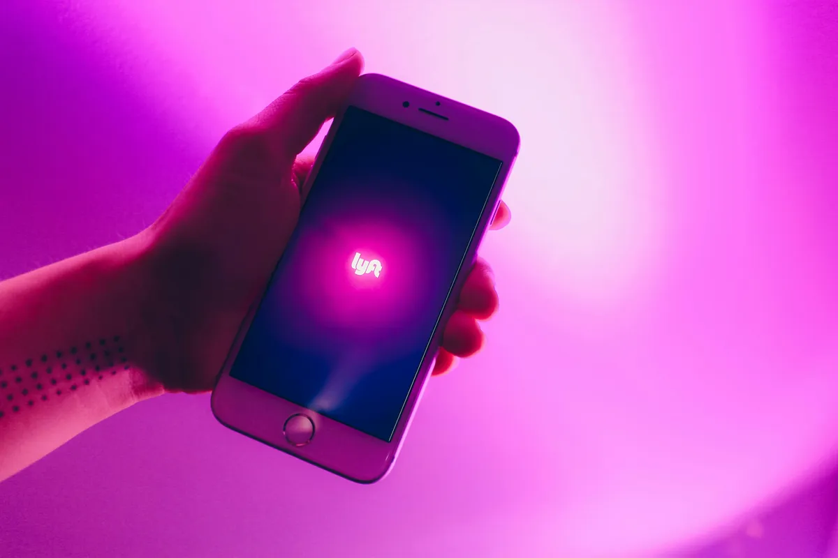 someone holding a cell phone with a pink light in the background