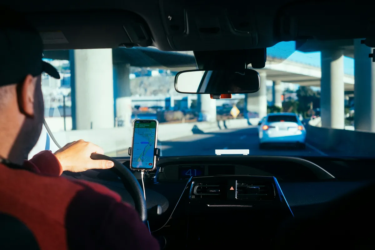 someone is driving a car with a cell phone in their hand