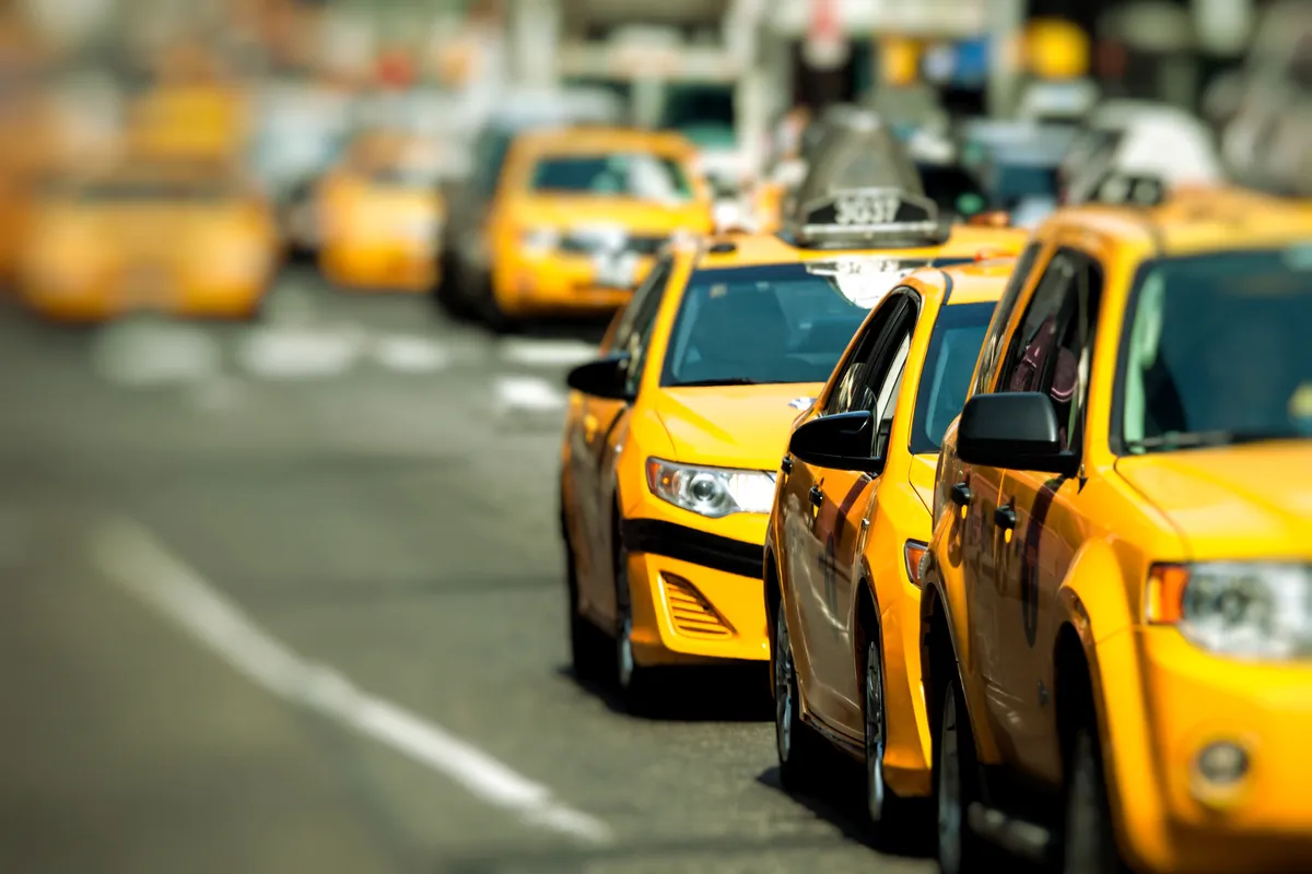 yellow cabs are lined up on the street in a line